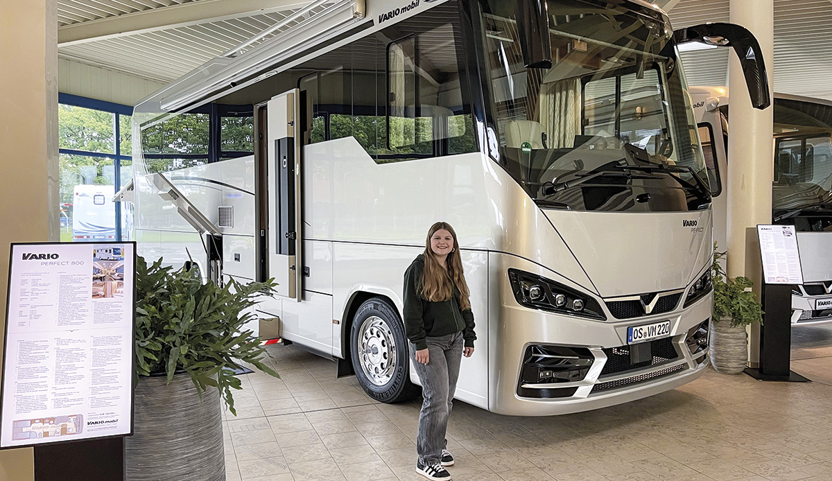 Schülerin Clarissa steht vor riesigem Reisemobil. Sie macht ein Praktikum im Marketing bei VARIOmobil im Fahrzeugbau und sammelt Fakten für den Blogartikel: Abenteuer Heavy Metal.