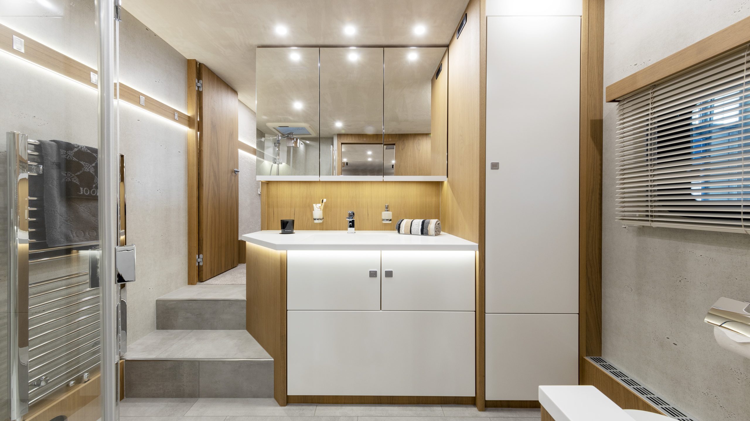 Frontal sichtbare Waschtischanlage im VARIO Alkoven mit Design-Handtuch-Heizkörper und Möbelbau in Nussbaum hell