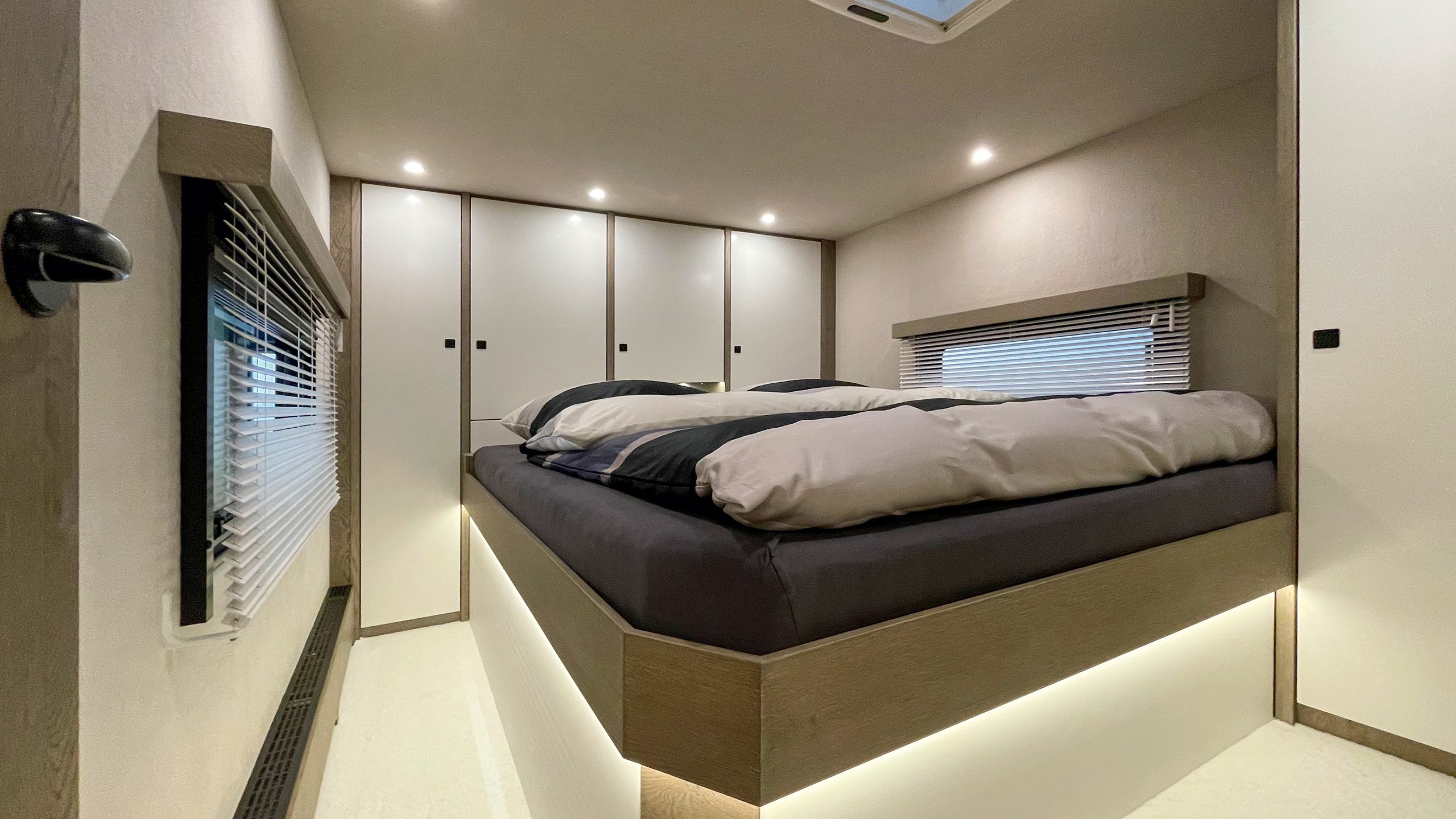 Queensbett und Reisemobil-Schlafraum in Nussbaum hell, Schleiflack-Türen in cremeweiß satiniert und viel Stauraum