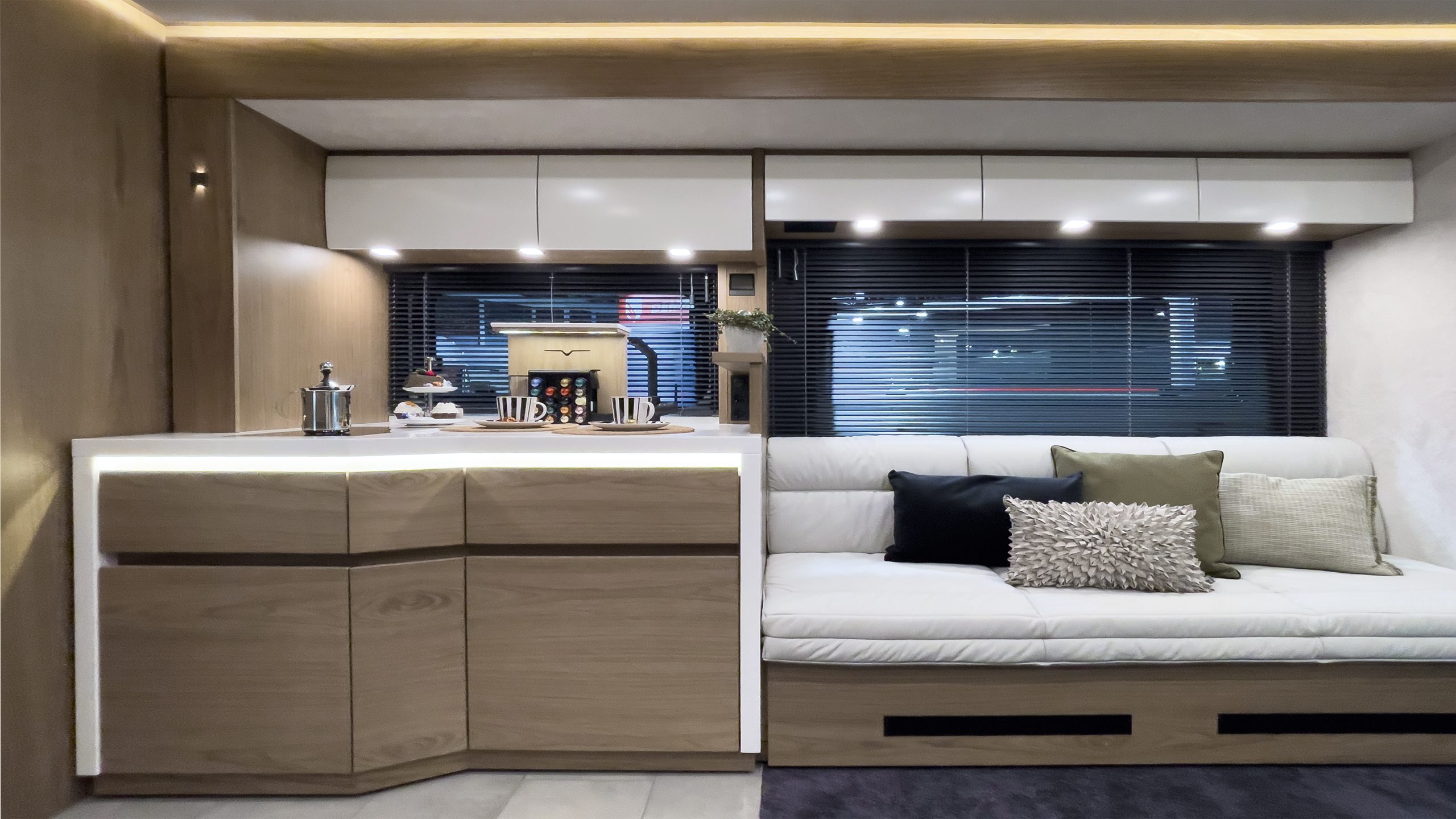 Große Reisemobil-Küche im SlideOut in cubeART Design: mit STARON pure white Arbeitsfläche, Interieur bentART Design in Edelholz Nussbaum hell, Nespresso-Maschine auf Lift, vollintegrierter EXQUISIT Geschirrspülmaschine und ausziehbarer Dickleder-Lounge mit Doppelbett-Funktion.