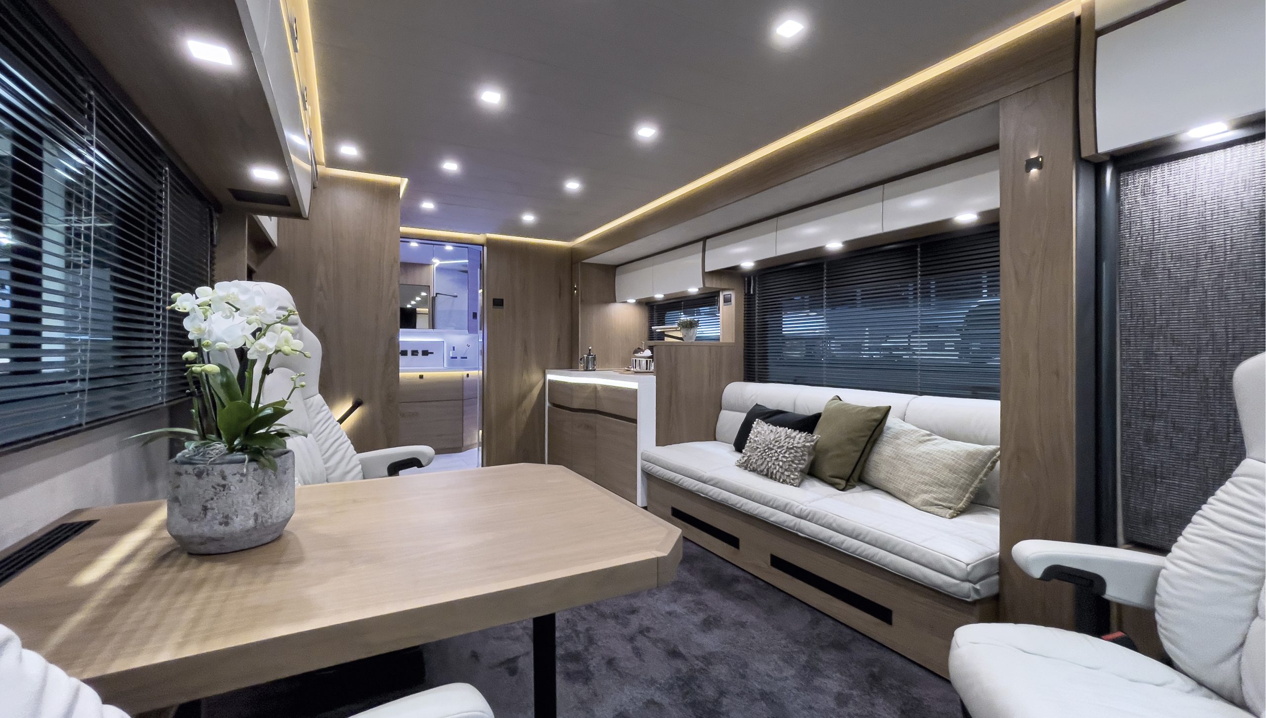 VARIO Perfect 1080 MB Actros 1846 – SALON in bentART Design mit Nussbaum hell, Dickleder Lounge in Cremeweiß und Blackline Interieur, indirekte Beleuchtung.